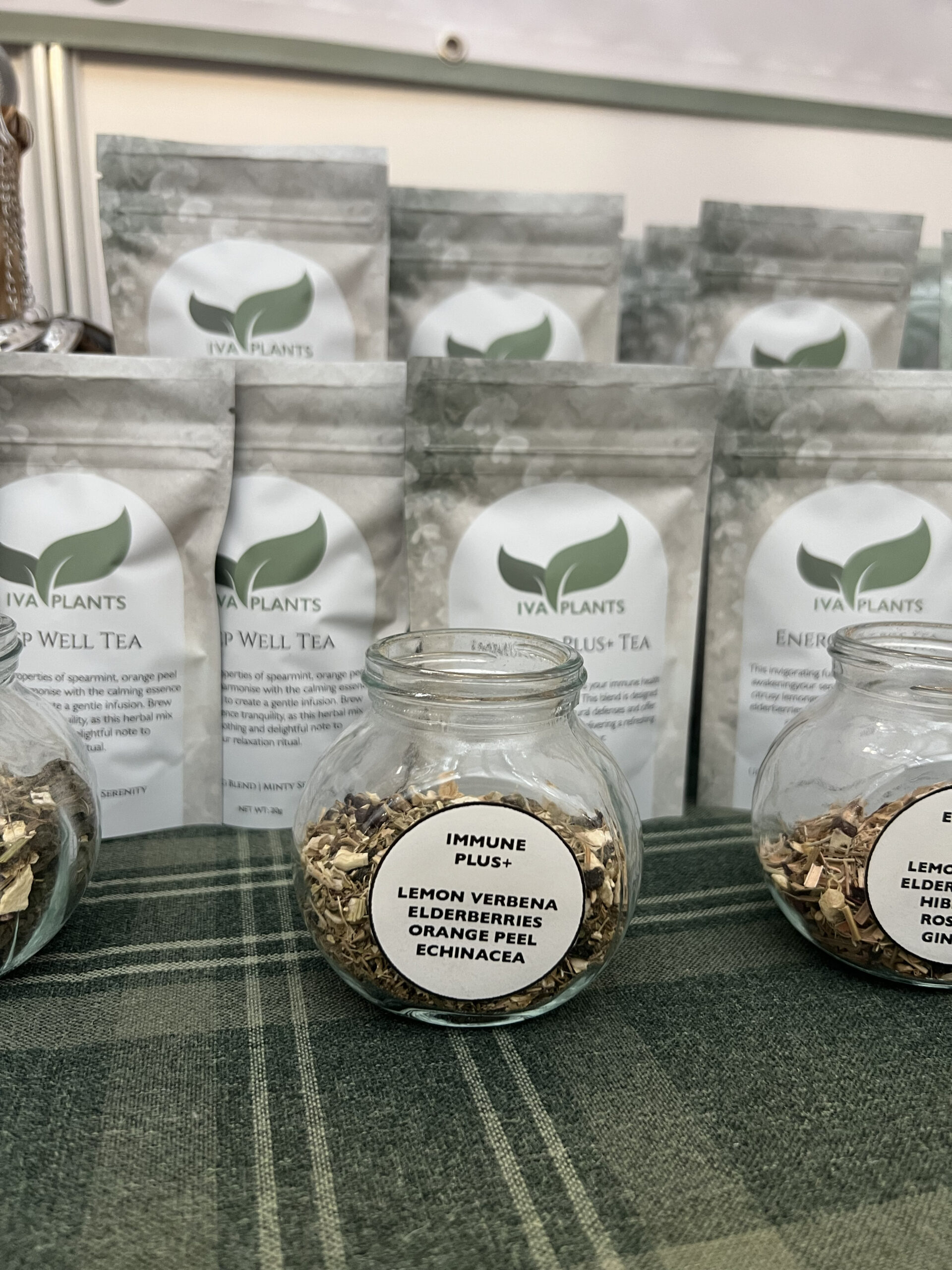 IVA Plants display at OM Yoga Show 2024, featuring glass jars of herbal, black Ceylon, and Japanese green teas, with new tea packaging in the background, Stand H4, Alexandra Palace, London